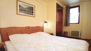 A bedroom with a large bed, a nightstand, a lamp, a window with curtains, and a picture on the wall. - Apartment for 6 people in Val Cenis (Val Cenis)