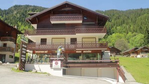 A multi-story building with a wooden facade, balconies, and a sign indicating it is a ski location.