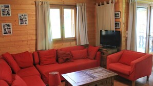 A cozy living room with a red sofa, a wooden coffee table, and a television.