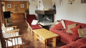 A cozy living room with a fireplace, wooden furniture, and a television. - Val Pierre apartment for 8 people (Châtel)