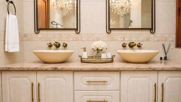 A bathroom with two large sinks, a mirror, a chandelier, and a towel rack.