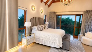 Un dormitorio con una cama grande, mesitas de noche, un candelabro y vistas al exterior.