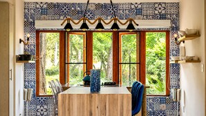 Un comedor con una mesa de madera, sillas y vistas amplias a través de ventanas grandes.