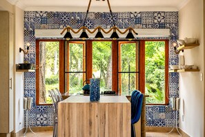 A dining area with a wooden table, chairs, and a view through large windows. - 156 Euphoria Boutique Villa - Euphoria Golf Estate & Hydro (Mookgopong)