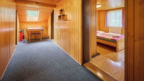 Una cabaña de madera con comedor, una pequeña cocina y un dormitorio con ventana.