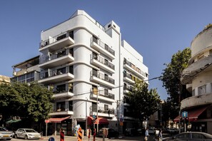 A multi-story building with balconies, a red awning, and a clear blue sky.