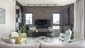 Un salon moderne avec un mur en briques, une cheminée, un téléviseur à écran plat et un canapé agrémenté de coussins.