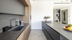 Une cuisine moderne avec un plan de travail foncé, des armoires en bois et une cuisinière intégrée.