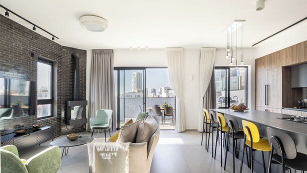 Un salon moderne comprenant un canapé, des fauteuils, un coin repas avec un bar et une cuisine.