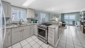 A modern kitchen with white cabinets, a built-in oven, and a large window. - Clearwater 2A (Gulf Shores)