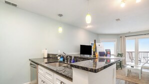 A modern kitchen with a granite countertop, stainless steel appliances, and pendant lighting.