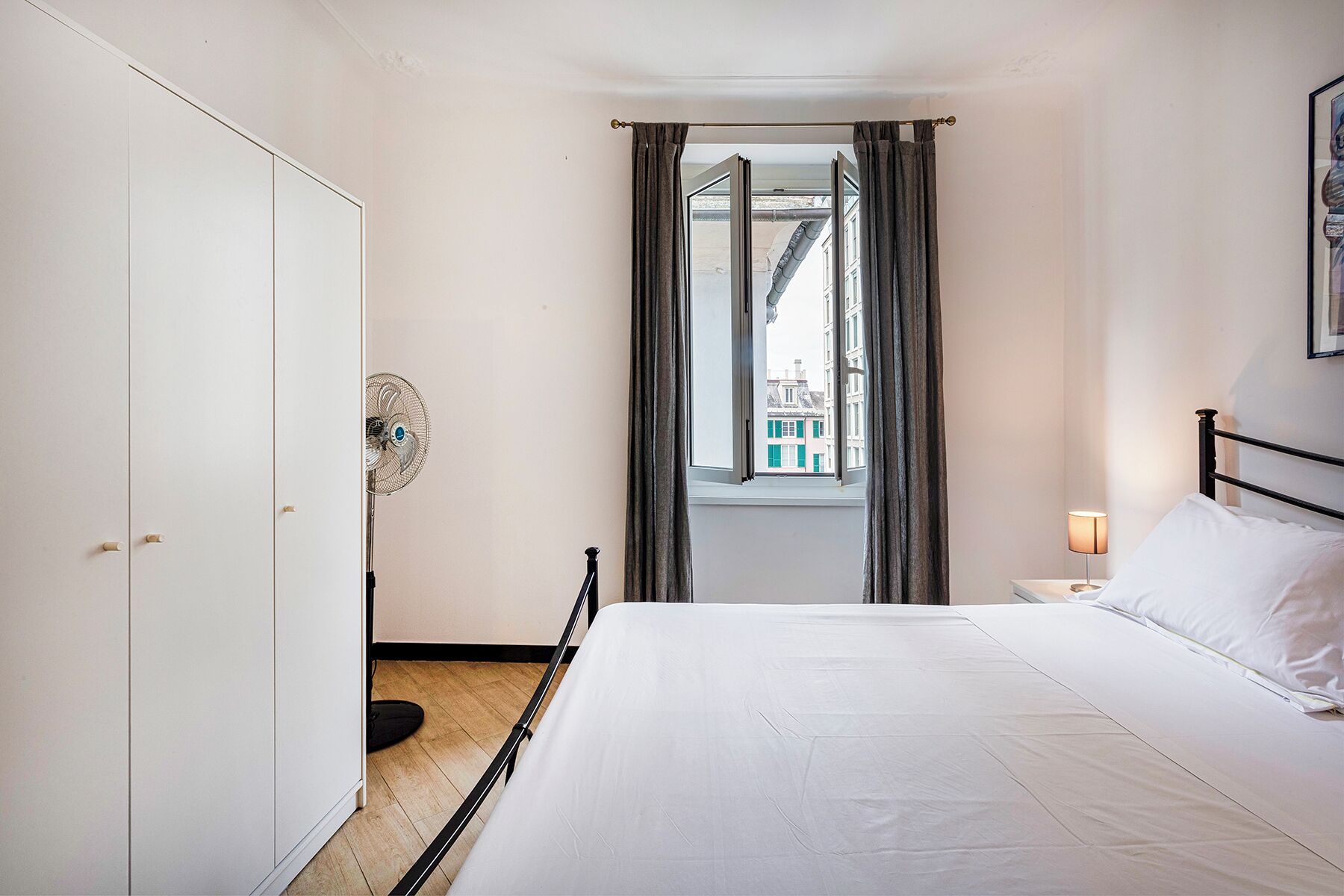 Une chambre à coucher avec un lit, une table de chevet, une fenêtre avec des rideaux et une porte.