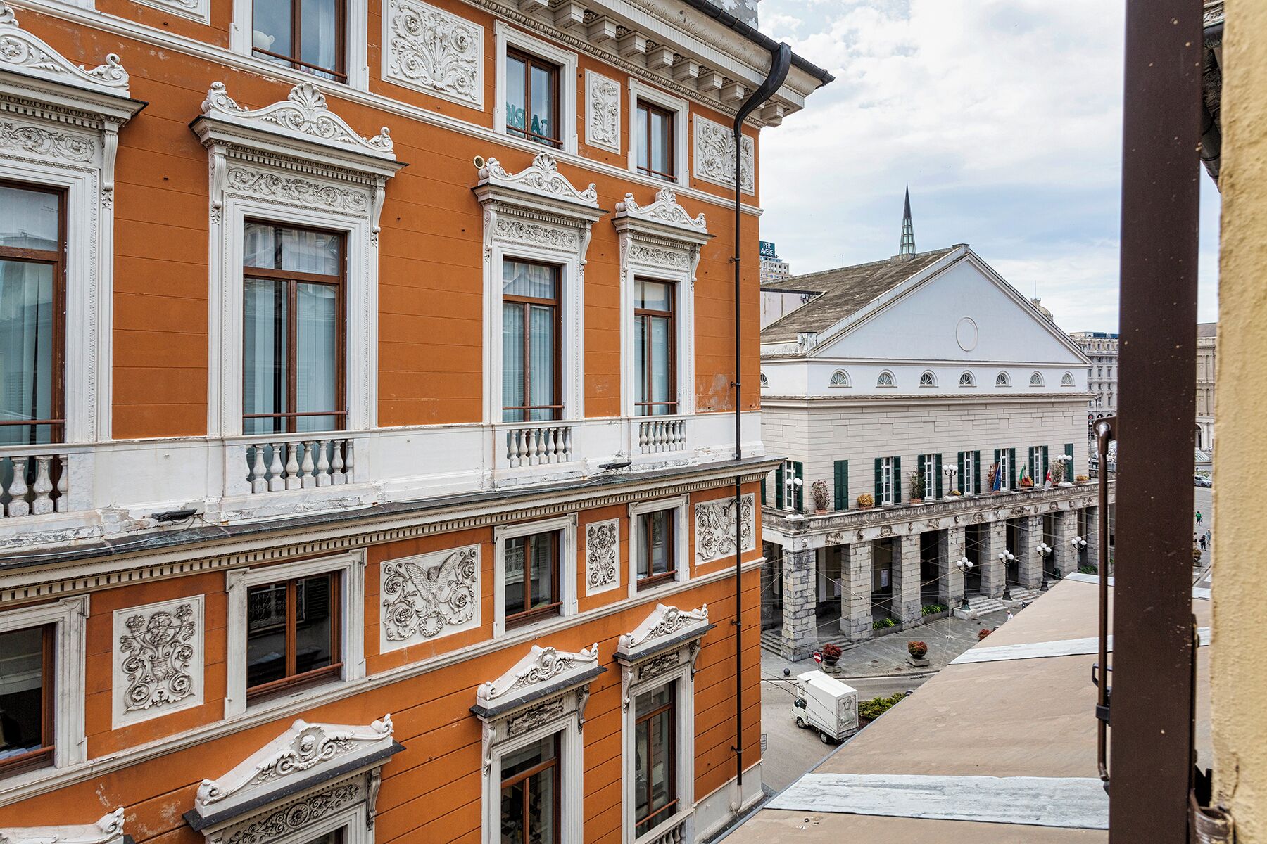 Un edificio storico con dettagli architettonici elaborati, una galleria coperta e una torre dell'orologio ben visibile sullo sfondo.