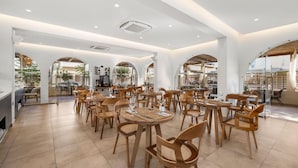 Un comedor amplio con varias mesas y sillas, ventanas grandes y un diseño de interiores moderno.