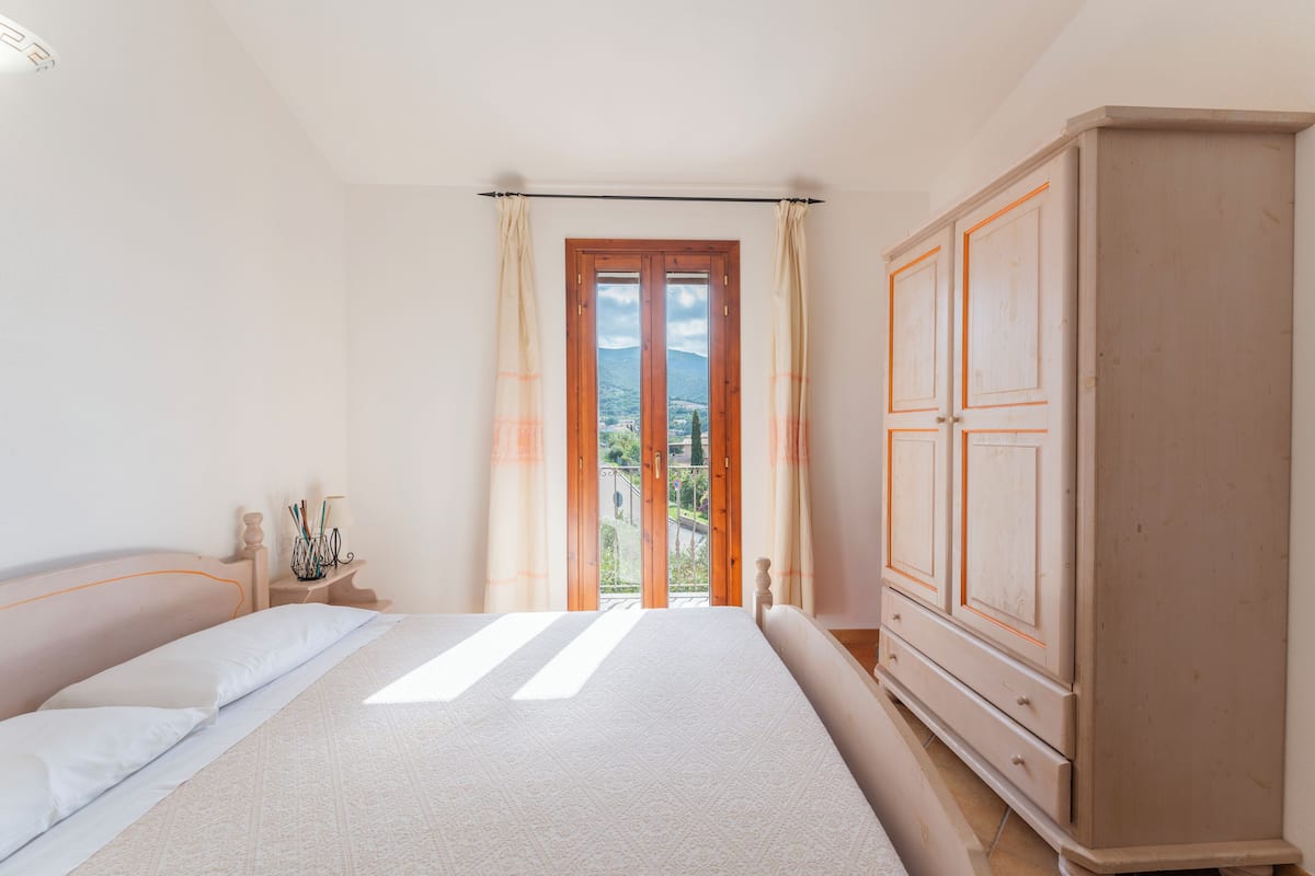 A bedroom with a large bed, a wardrobe, and a window with curtains.