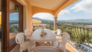Un balcon avec une table et des chaises, offrant une vue sur un paysage montagneux.