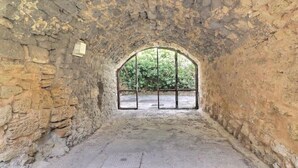 An arched stone room with a view of greenery outside.