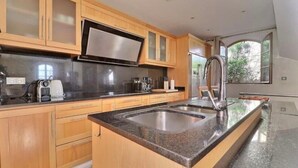 A modern kitchen with wooden cabinets, a stainless steel sink, and a large window providing natural light.