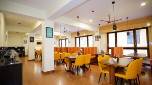 Un restaurant avec des planchers en bois, des chaises jaunes et des banquettes orange.