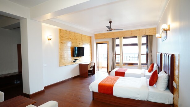 Une chambre d’hôtel avec deux lits, un bureau, une télévision et un balcon avec vue.