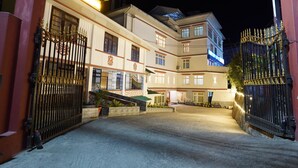 Un hôtel à plusieurs étages, doté d’une entrée sécurisée par un portail, d’une façade bien éclairée et d’une cour intérieure.