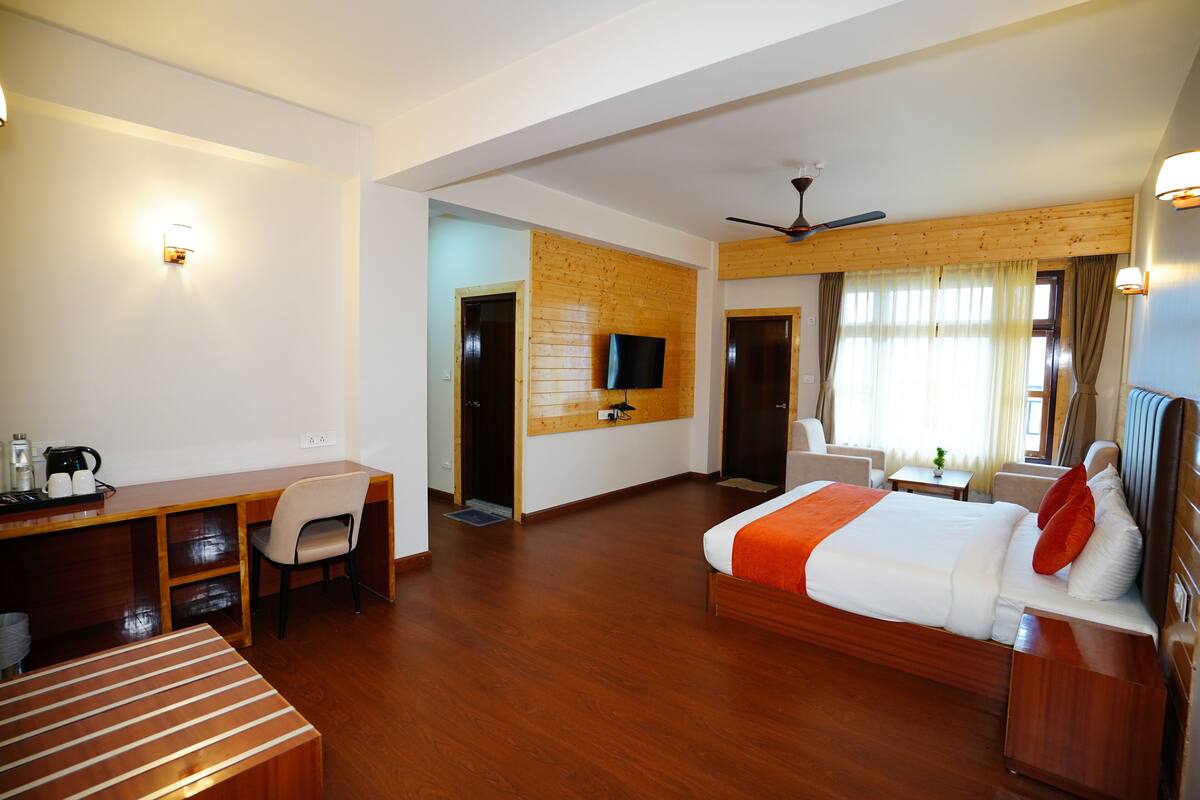 A hotel room with a bed, desk, chair, television, and a wooden accent wall.