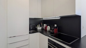 A modern kitchen with white cabinetry, a black countertop, and a patterned floor. - Attic apartment 2 minutes from the center, with a dream terrace (Leukerbad)