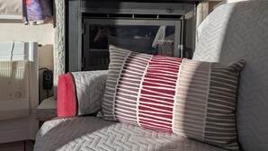 A cozy living area with a fireplace, a comfortable sofa, and a window with curtains. - Attic apartment 2 minutes from the center, with a dream terrace (Leukerbad)