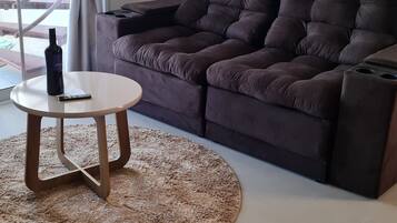 A modern living room with a dark brown sofa, a round wooden coffee table, and a textured rug.