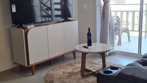 Moderni olohuone, jossa on litteänäyttöinen televisio, pyöreä sohvapöytä ja sohva.