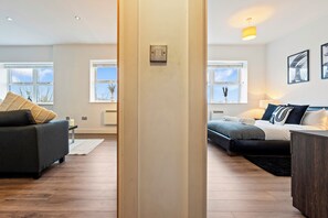 Un salon moderne avec un canapé, un lit et une table basse. Il y a des fenêtres qui donnent sur l’extérieur.