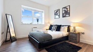 Ein modernes Schlafzimmer mit einem großen Bett, Nachttischen, einem Spiegel und Kunstwerken an den Wänden.