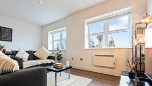 Ein modernes Wohnzimmer mit Sofa, Couchtisch und Blick auf ein Gebäude durch große Fenster.