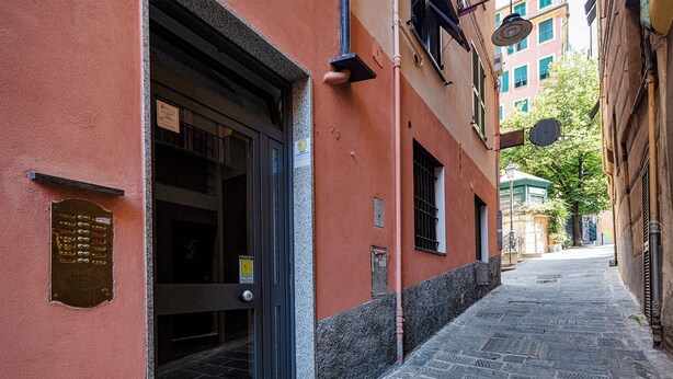 Eine enge Kopfsteinpflasterstraße mit einem Gebäude, das eine Metalttür und eine kleine Wandplakette besitzt.