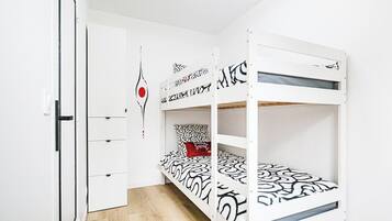 Un lit superposé avec une couvre-lit à motifs, un oreiller rouge et une décoration murale.