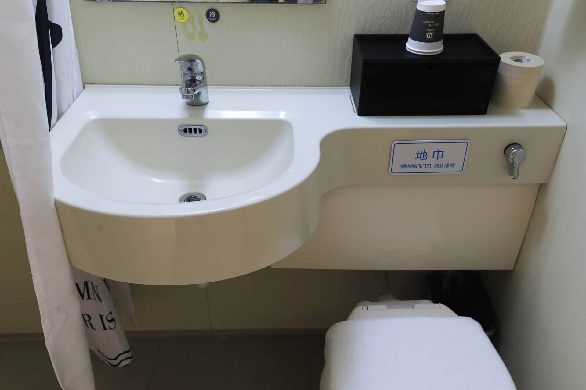 A bathroom sink with a faucet, a black soap dispenser, and a toilet.