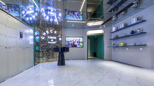 Un hall d’entrée moderne doté d’un comptoir d’enregistrement, d’un mur d’écrans numériques et d’un sol carrelé, propre et élégant.