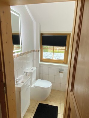 A compact bathroom with a toilet, sink, and window.