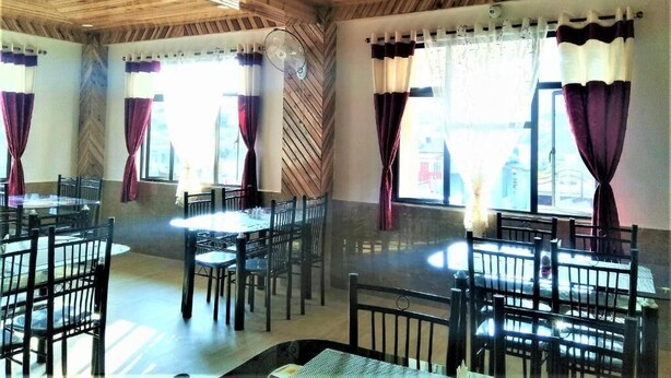 A restaurant with wooden ceiling beams, round tables, and chairs. - Sulawado Resort (Shillong)