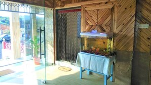 A room with a wooden ceiling, a glass door leading outside, and a table with a white tablecloth. - Sulawado Resort (Shillong)