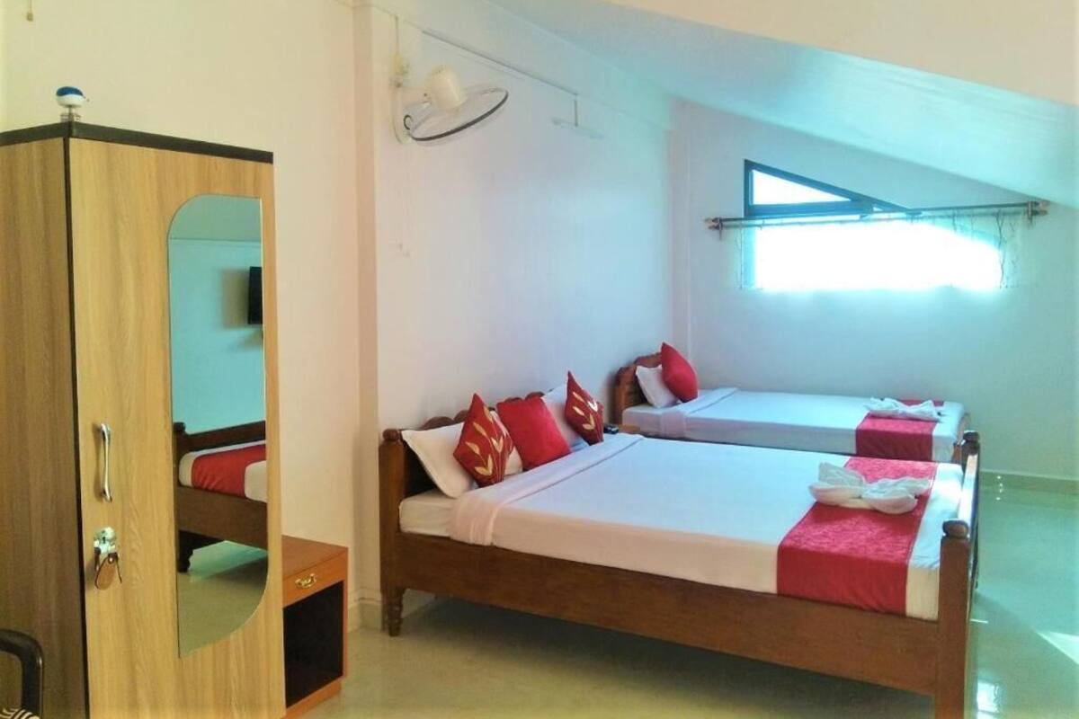 A room with two beds, a wardrobe, a mirror, a ceiling fan, and a window with a view.