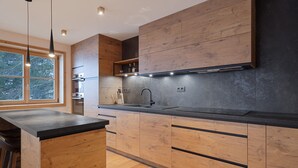 A modern kitchen with wooden cabinetry, a black countertop, and a large window.