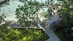 A lakeside deck with seating and a wooden pathway leading to the water.