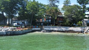 A waterfront property with a dock, a gazebo, and a multi-level house with balconies.