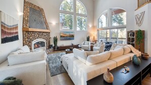 A spacious living room with a stone fireplace, large windows, and a cozy seating area.