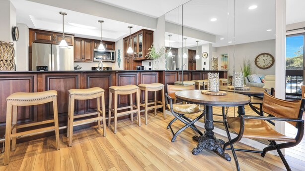 A modern kitchen with wooden bar stools, a round dining table, and pendant lighting.