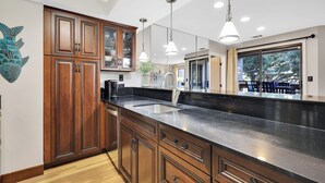 A kitchen with wooden cabinets, a black countertop, and pendant lighting.