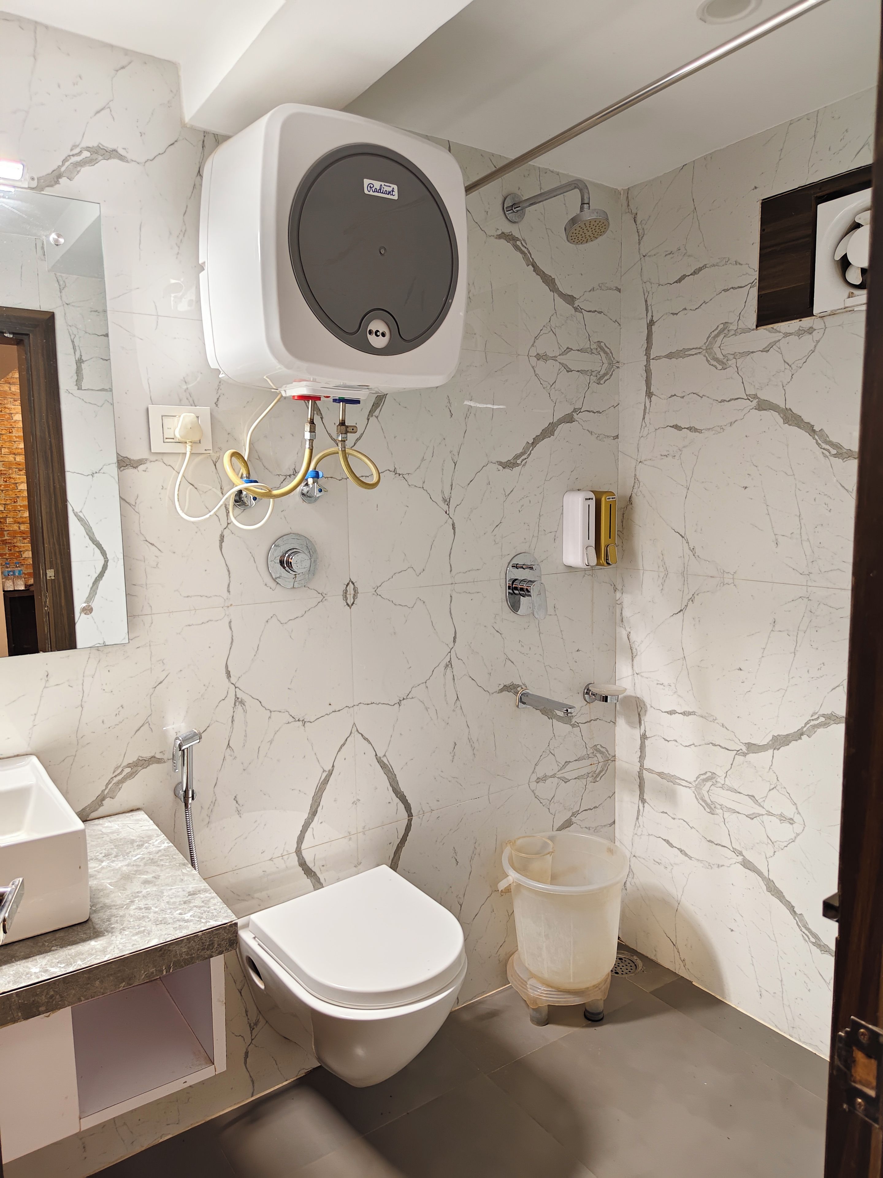 Ein Badezimmer mit Toilette, Waschbecken, Dusche und Warmwasserbereiter.