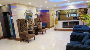 A lobby with a reception desk, multiple seating areas, and a decorative wall with clocks. - hotel sainison manali (Manali)