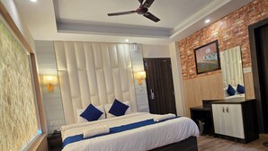 A modern hotel room with a large bed, a ceiling fan, a wooden floor, and a brick wall. - hotel sainison manali (Manali)
